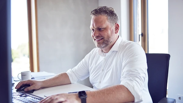 Mitarbeiter arbeitet am Computer in hellem Büro