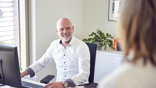Mitarbeiter arbeitet am Schreibtisch mit Unterlagen und Computer