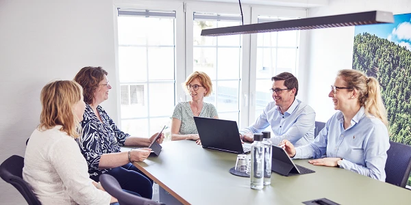 Besprechung von fünf Teammitgliedern in einem Konferenzraum