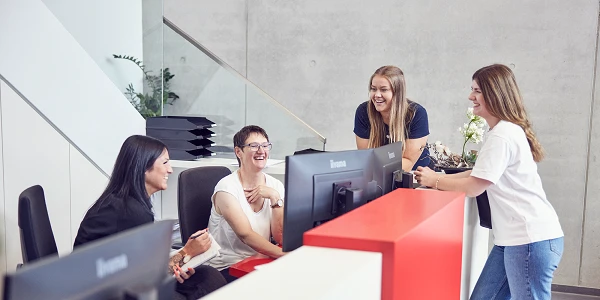Vier Mitarbeiterinnen lachen gemeinsam an der Rezeption