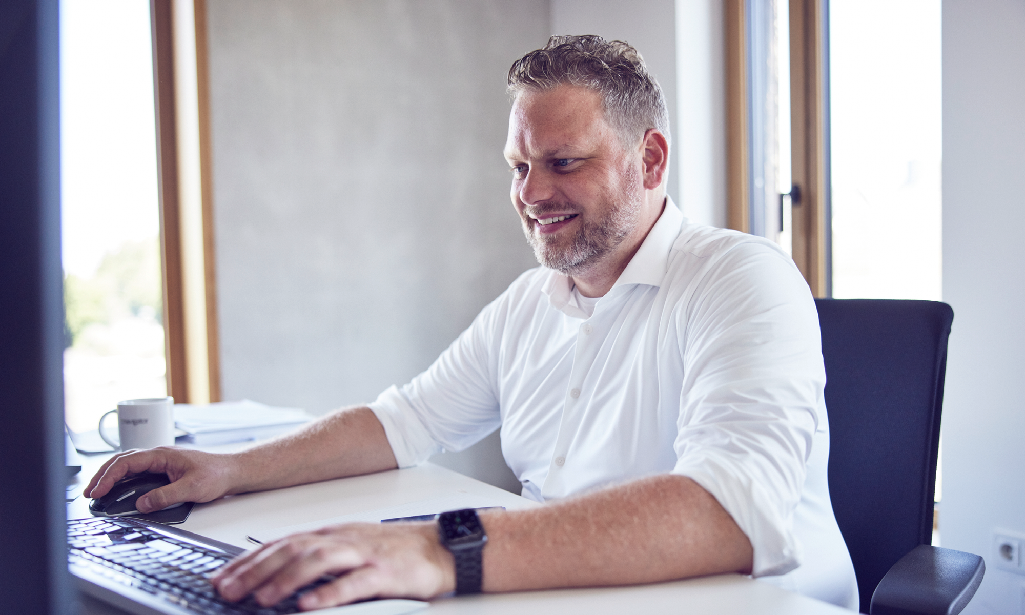 Mitarbeiter arbeitet am Computer in hellem Büro