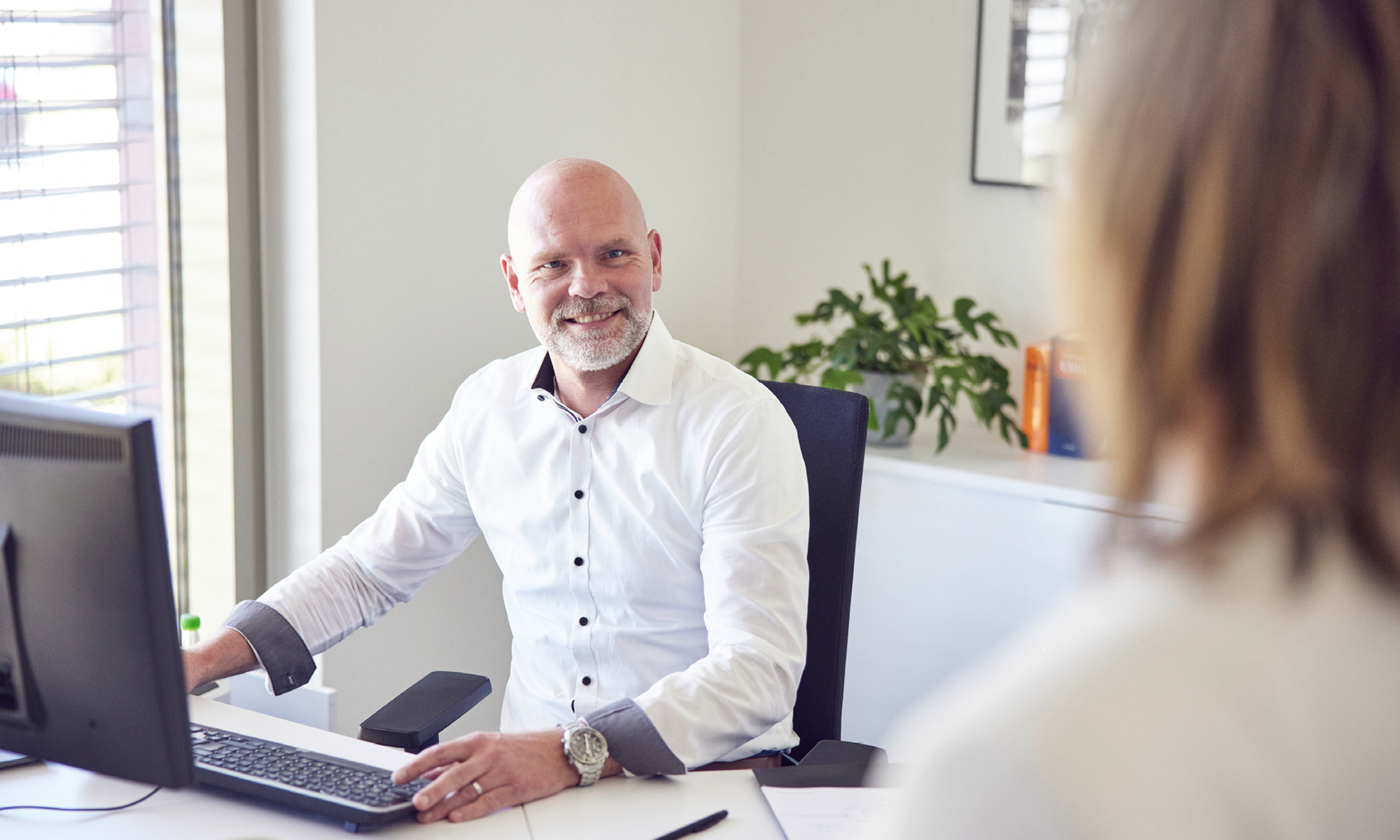 Mitarbeiter arbeitet am Schreibtisch mit Unterlagen und Computer