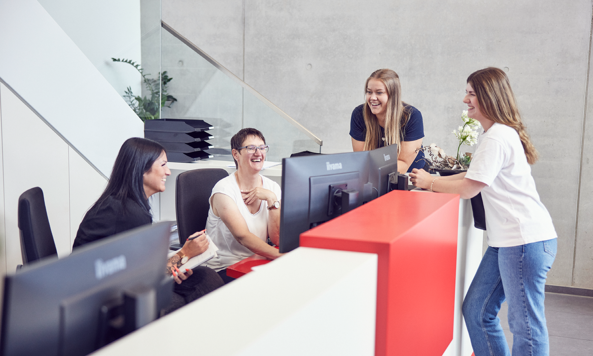 Vier Mitarbeiterinnen lachen gemeinsam an der Rezeption